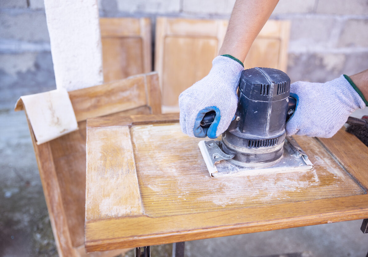 Woman Refinish Wood Furniture Using an electric Sander tool